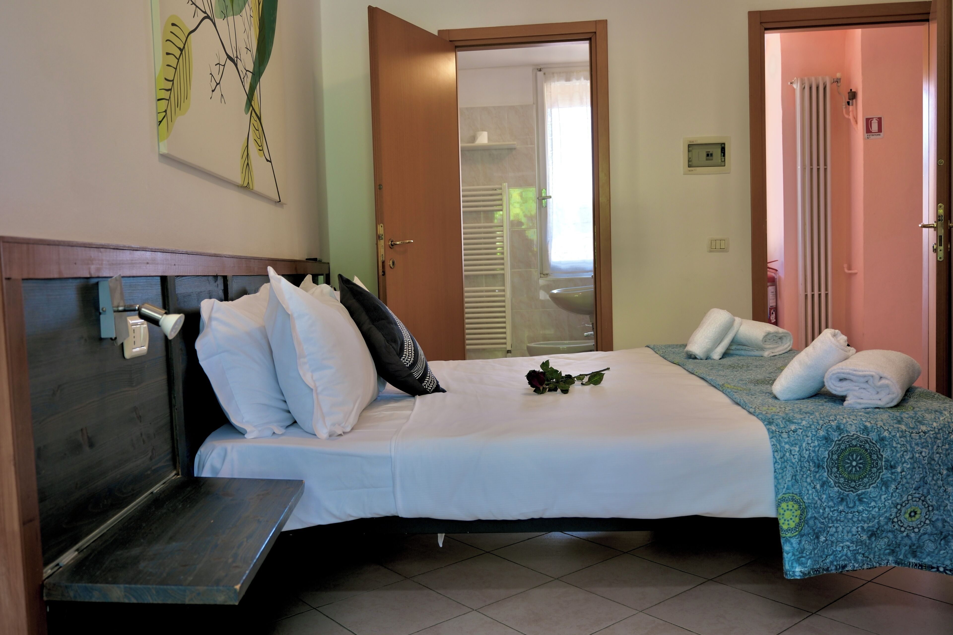Une chambre d’hôtel avec un lit, une table de chevet et un espace douche visible à travers une porte ouverte.