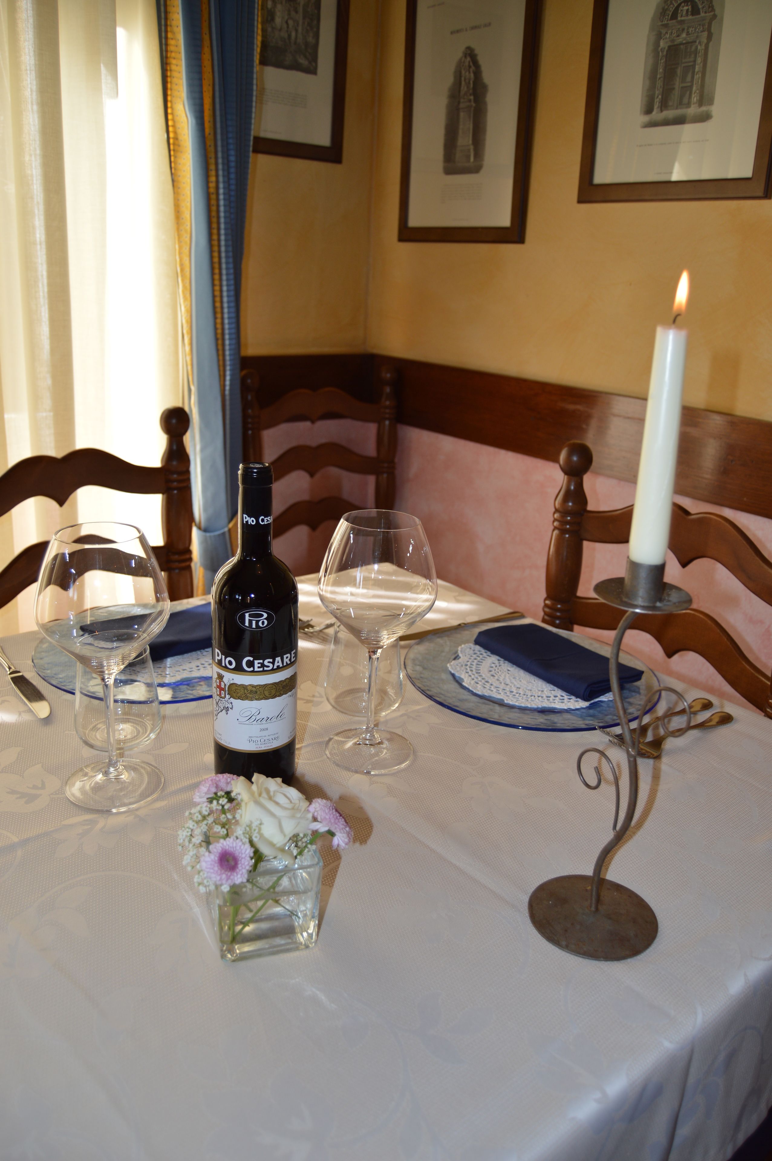 A dining table set with wine glasses, a bottle of wine, a candle, and a small vase with flowers.