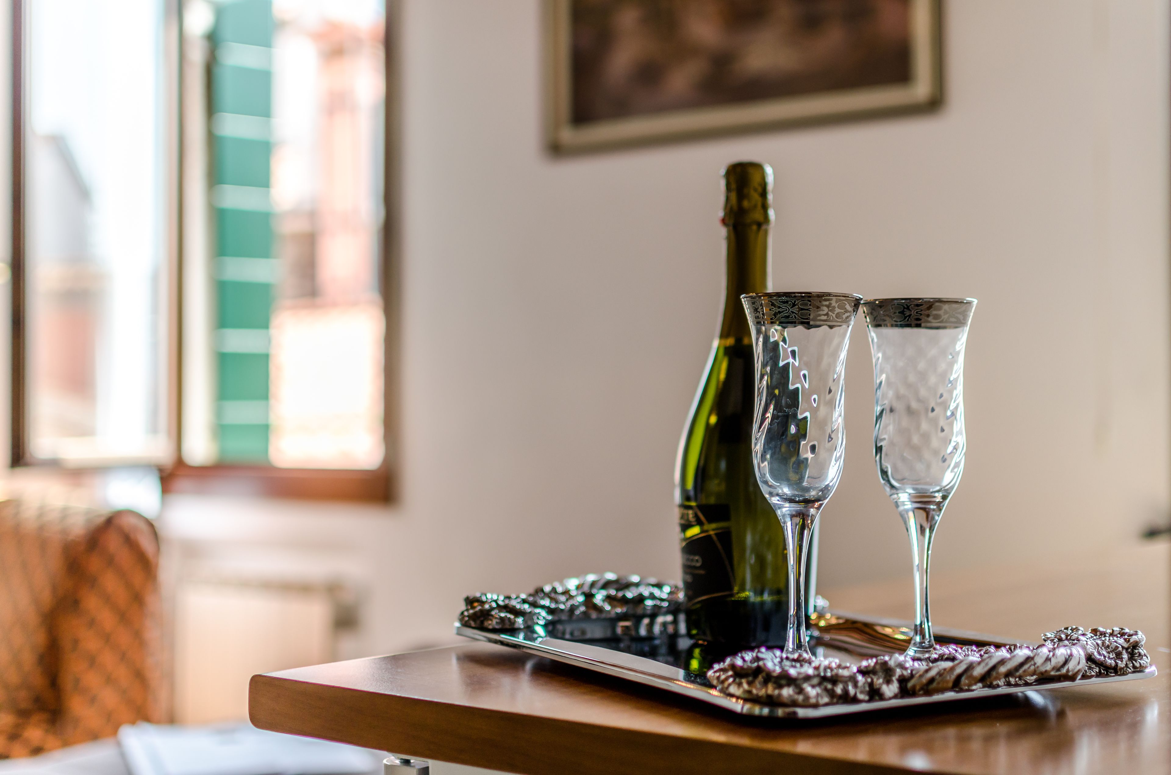A bottle of wine and two glasses on a tray with a decorative mat.