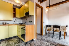 Une cuisine avec des meubles de couleur jaune, un fourneau et un coin repas comprenant une table et des chaises.
