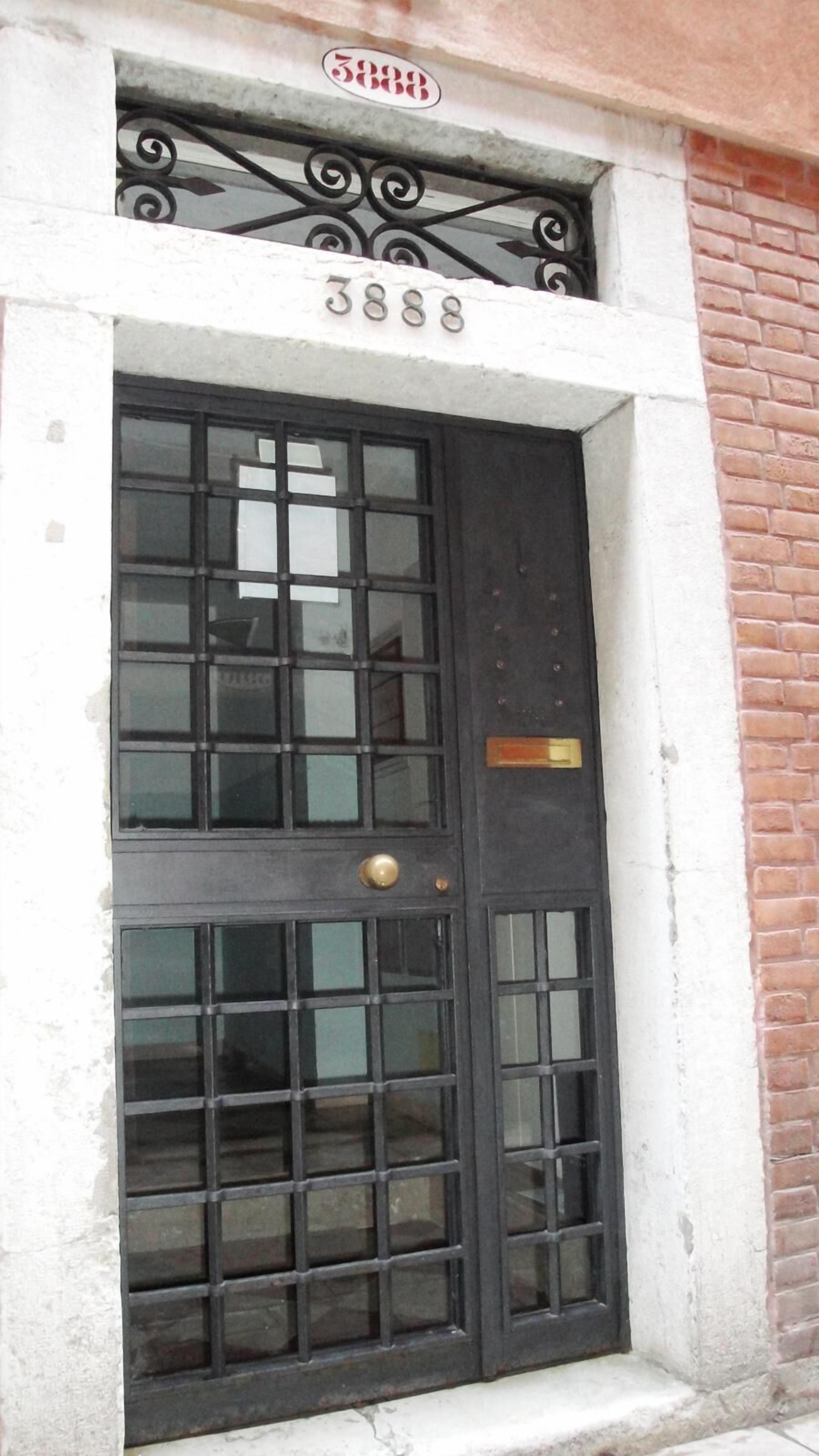 A black door with a brass handle and a small brass plate above it.