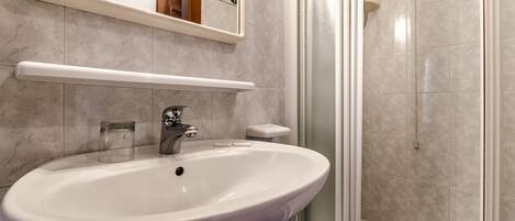 A bathroom with a white sink, a mirror, and a shower area.