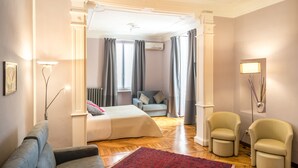 A hotel room with a bed, a sofa, two armchairs, a red rug, and a floor lamp. - Hotel Alpi Resort (Turin)