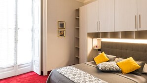 A bedroom with a bed, a red carpet, a sliding glass door, and a wardrobe with built-in lighting. - Hotel Alpi Resort (Turin)