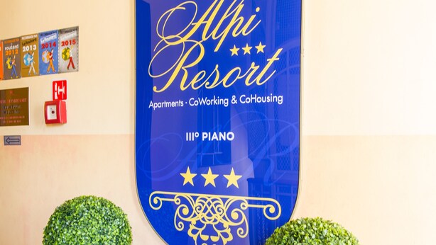 A hotel sign with the name "Alfi Resort" and mentions "Apartments, CoWorking & CoHousing" along with "III° Piano". - Hotel Alpi Resort (Turin)
