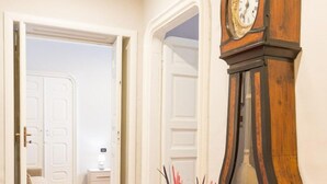 A room with a red carpet, a wooden grandfather clock, and a vase with pink and red sticks. - Hotel Alpi Resort (Turin)