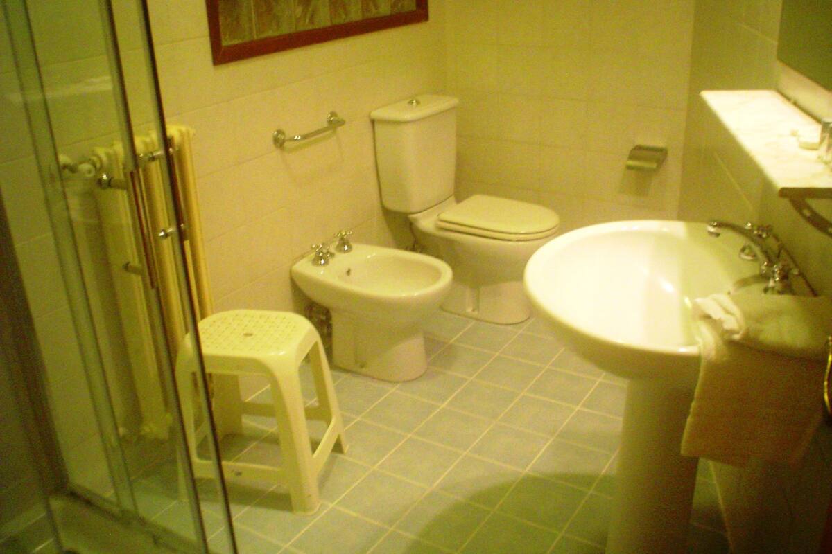 A bathroom with a glass shower enclosure, a toilet, a bidet, and a sink.