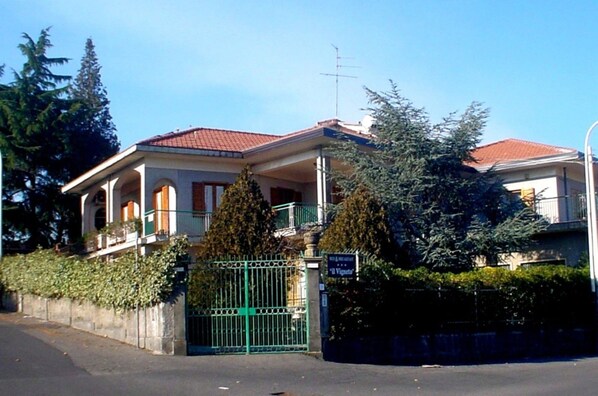 Una casa a due piani con tetto in tegole rosse, un balcone e un cancello.