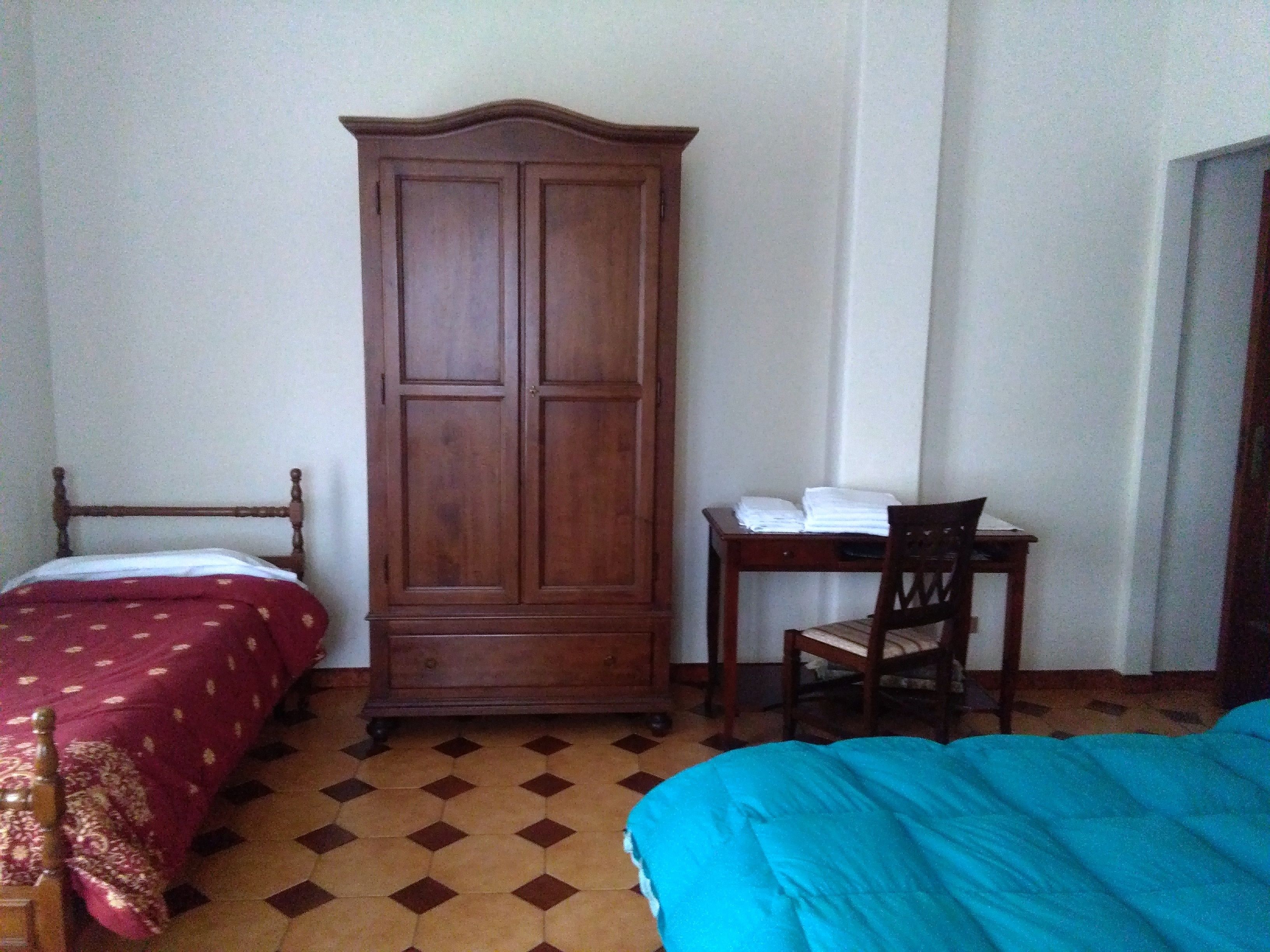 Een kamer met twee bedden, een kledingkast en een bureau met stoel.