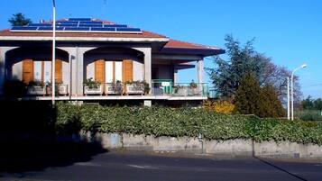 A building with a flat roof, solar panels, and a balcony with potted plants.