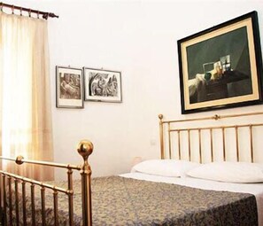 A bedroom with a bed, a headboard, a curtain, and two framed pictures on the wall. - Hotel Morlacchi (Perugia)