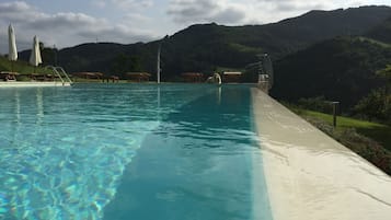 Piscina all'aperto, una piscina a sfioro, lettini