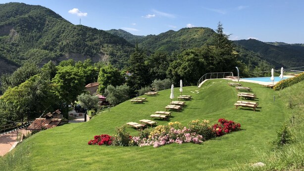 Un jardin aménagé sur une colline, avec une piscine, des chaises longues et un belvédère.