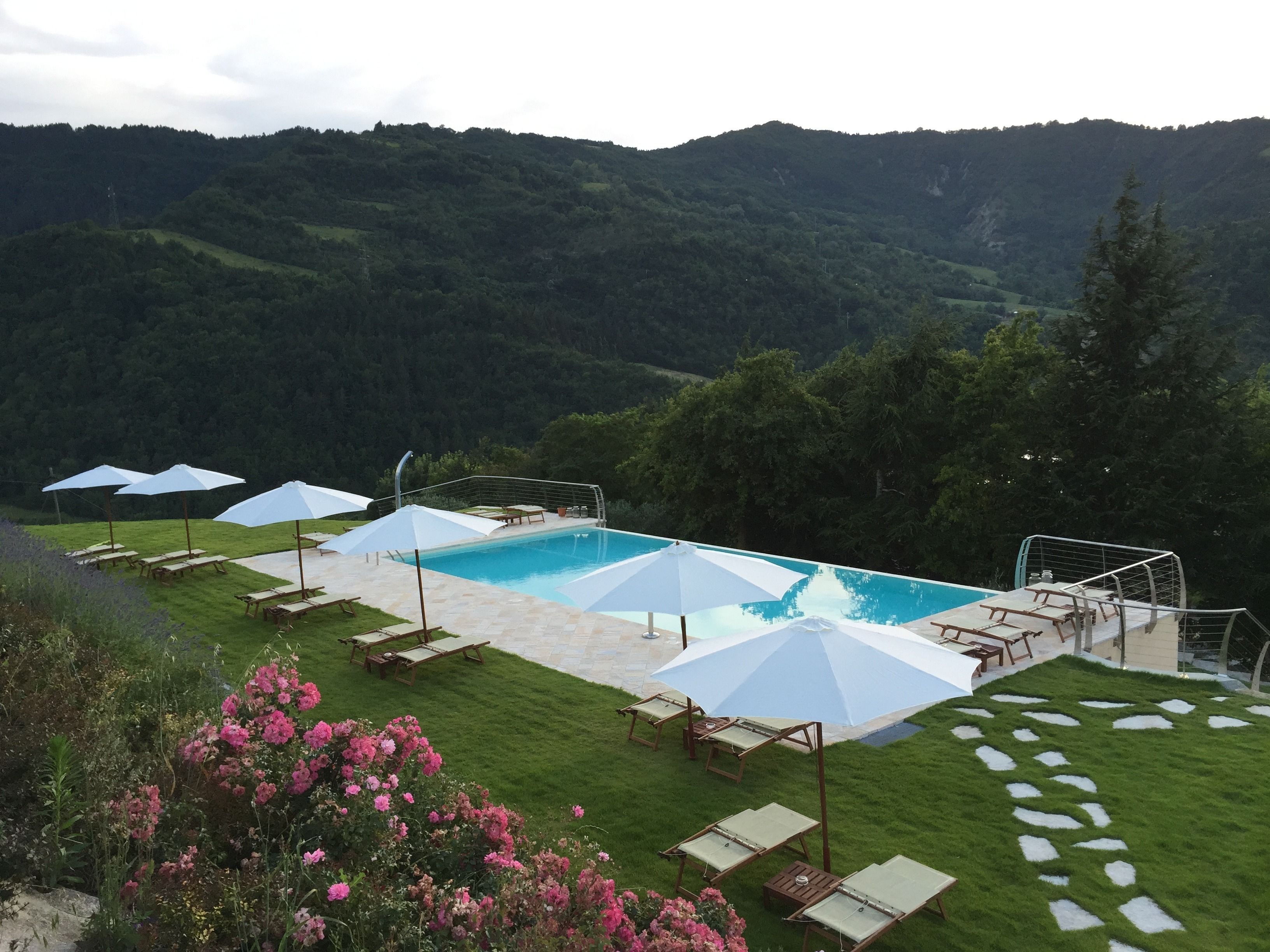 Piscina all'aperto, una piscina a sfioro, lettini