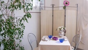 A dining area with a table set for two, a potted plant, and a decorative vase with flowers. - Girasole House (Florence)