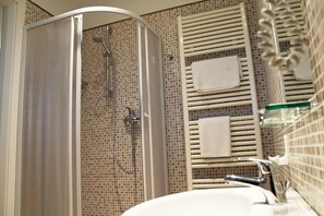 A bathroom with a glass shower enclosure, a white sink, and a towel rack with two towels. - Hotel Saint Tropez Riccione (Riccione)