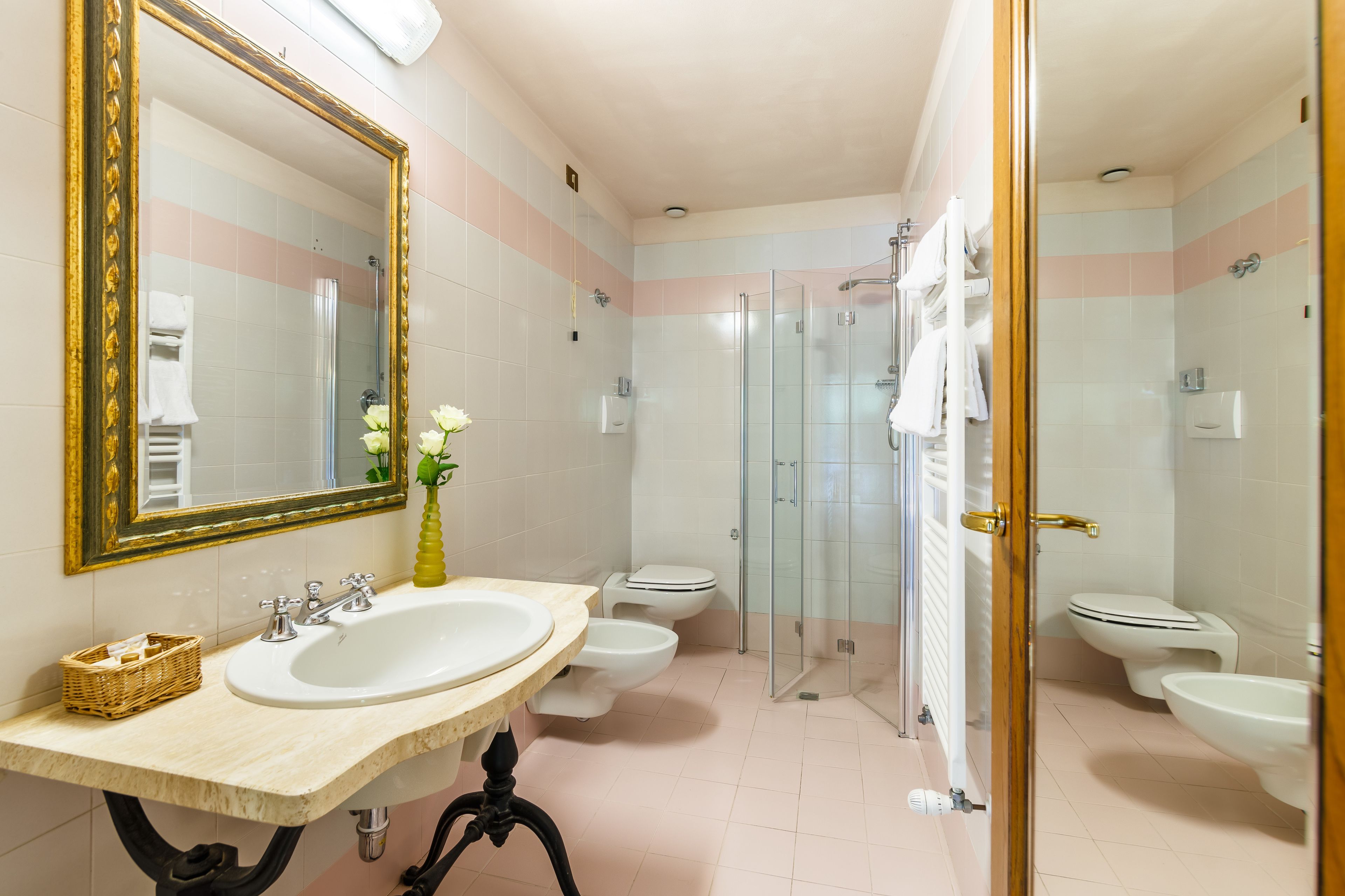 Une salle de bain avec un grand miroir, deux lavabos, une douche et des toilettes.