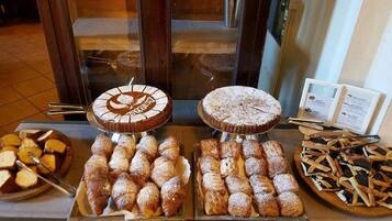 Un buffet proposant une variété de produits de boulangerie, notamment des pâtisseries, du pain et des desserts.