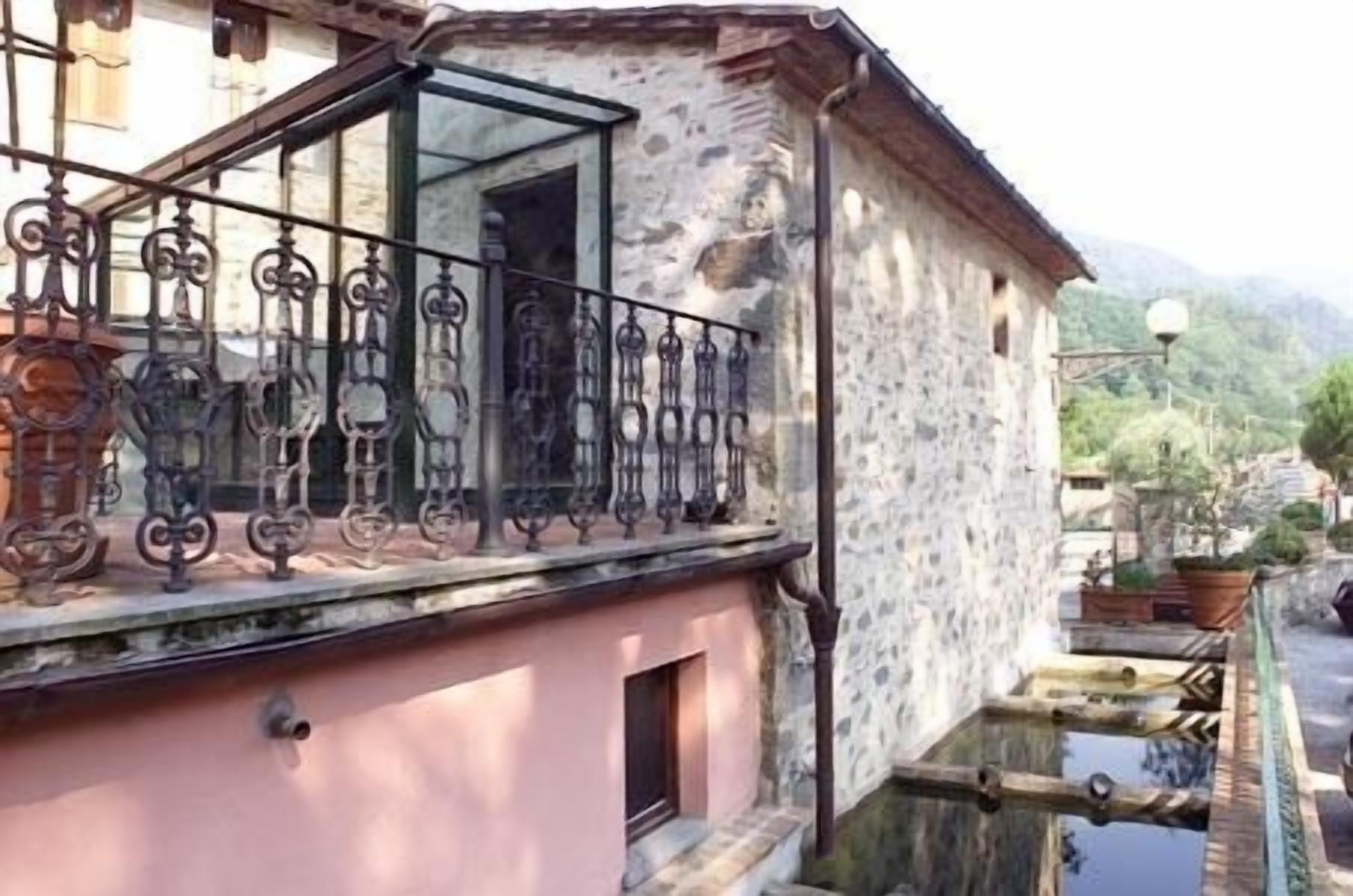 A stone building with a balcony featuring wrought iron railings.