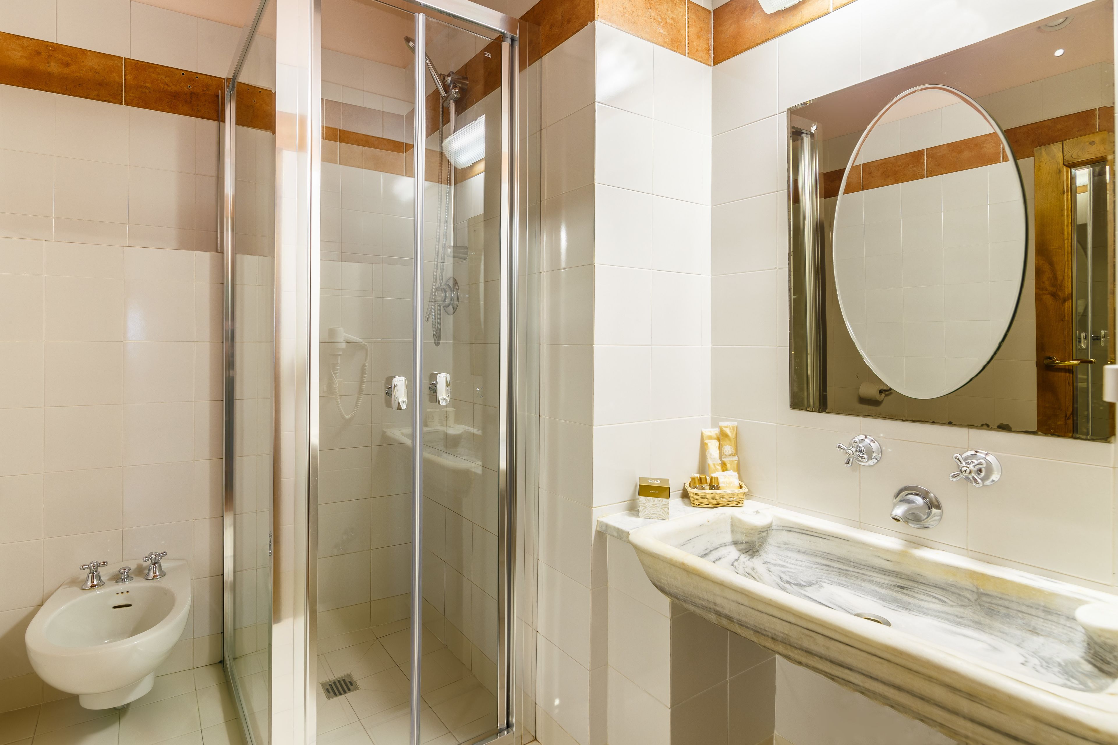Ein modernes Badezimmer mit einer Duschkabine, einem Bidet und einem Marmorwaschbecken.