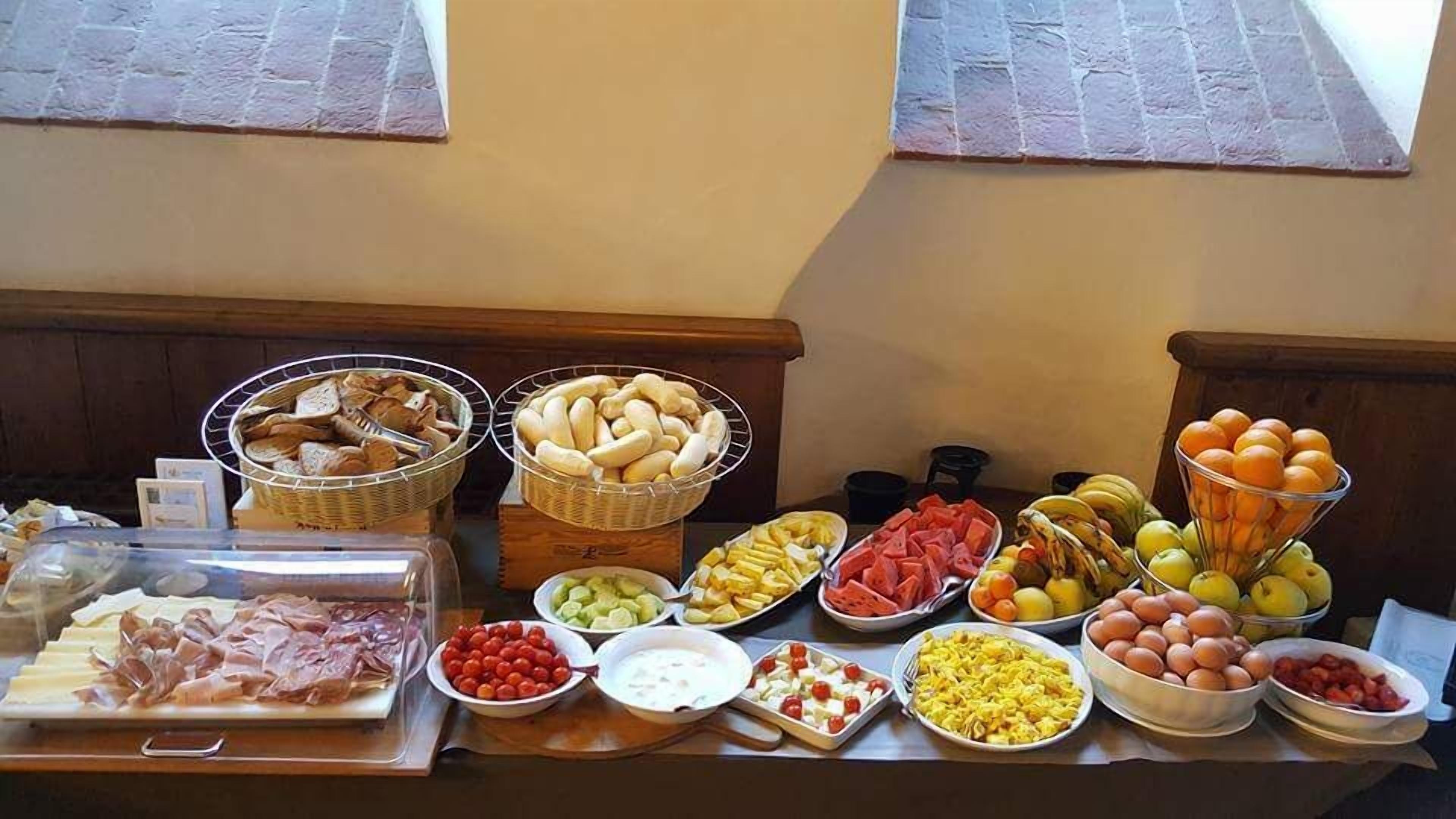 Une table de buffet proposant une variété d’aliments, notamment des viandes, des fromages, des fruits et des légumes.