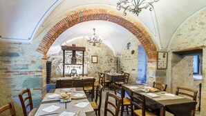 A dining area with brick arches, wooden tables, and chairs. - Villaggio Albergo San Lorenzo e Santa Caterina (Pescia)