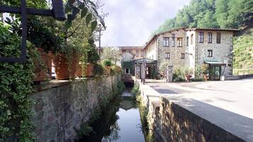 Un edificio in pietra con una zona salotto all'aperto coperta e un stretto canale d'acqua.