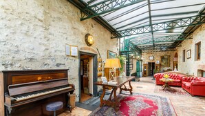 A spacious lobby with a grand piano, a red leather sofa, and a patterned rug. - Villaggio Albergo San Lorenzo e Santa Caterina (Pescia)