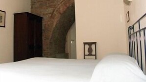 Un dormitorio con una cama, un armario de madera, una pared de ladrillo y un pequeño marco de fotos en la pared.