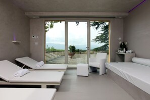 A modern spa room with two massage tables, a single chair, and a bed. - Villa Poggio Bartoli (Vicchio)