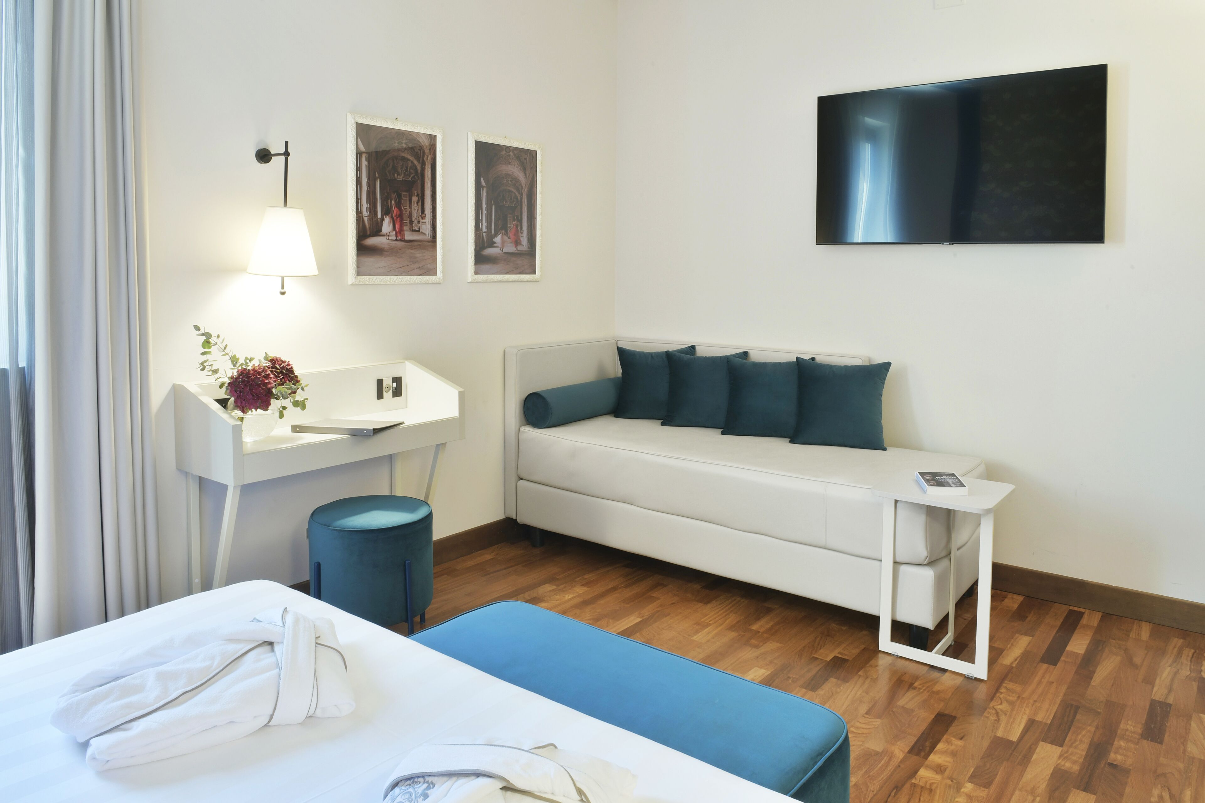 Una habitación de hotel moderna con una cama, un sofá, un escritorio pequeño, una lámpara y un televisor de pantalla plana.