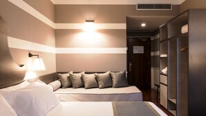 Habitación de hotel con cama, sofá, armario y una lámpara de pared.
