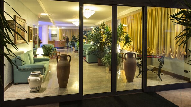 Un vestíbulo de hotel con un sofá, dos jarrones grandes y una mesa de comedor.