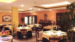 Un restaurante con varias mesas dispuestas para comer, una zona de bar y una variedad de plantas y decoraciones.