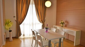A dining area with a white table and chairs, a vase with flowers, and a wooden wall. - Grand Eurhotel (Montesilvano)