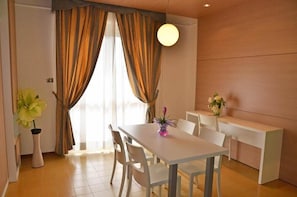 A dining area with a white table and chairs, a vase with flowers, and a wooden wall. - Grand Eurhotel (Montesilvano)