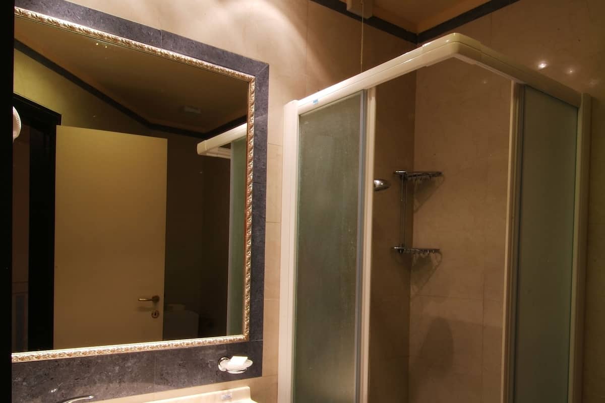 A bathroom with a sink, mirror, and shower.