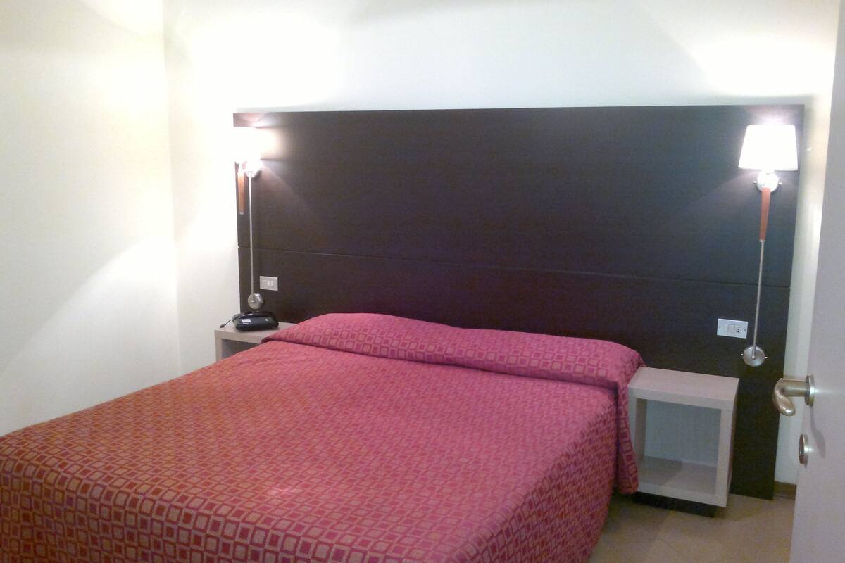 A bedroom with a bed, nightstand, and bedside lamps.