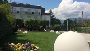 Zona residencial con una casa moderna de dos pisos, césped bien cuidado y esculturas esféricas grandes.