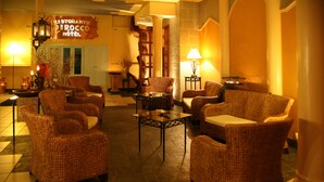 Un vestíbulo con muebles de mimbre, una mesa central y un letrero que indica 'Ristorante Dirocco Hotel'.