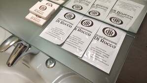 A glass-topped table with several white business cards and small white boxes, each featuring the logo and name of Hotel Ristorante Di Rocco.