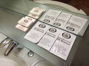 A glass-topped table with several white business cards and small white boxes, each featuring the logo and name of Hotel Ristorante Di Rocco.