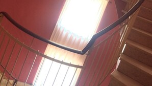 Una escalera de caracol con barandillas metálicas y una pared roja.