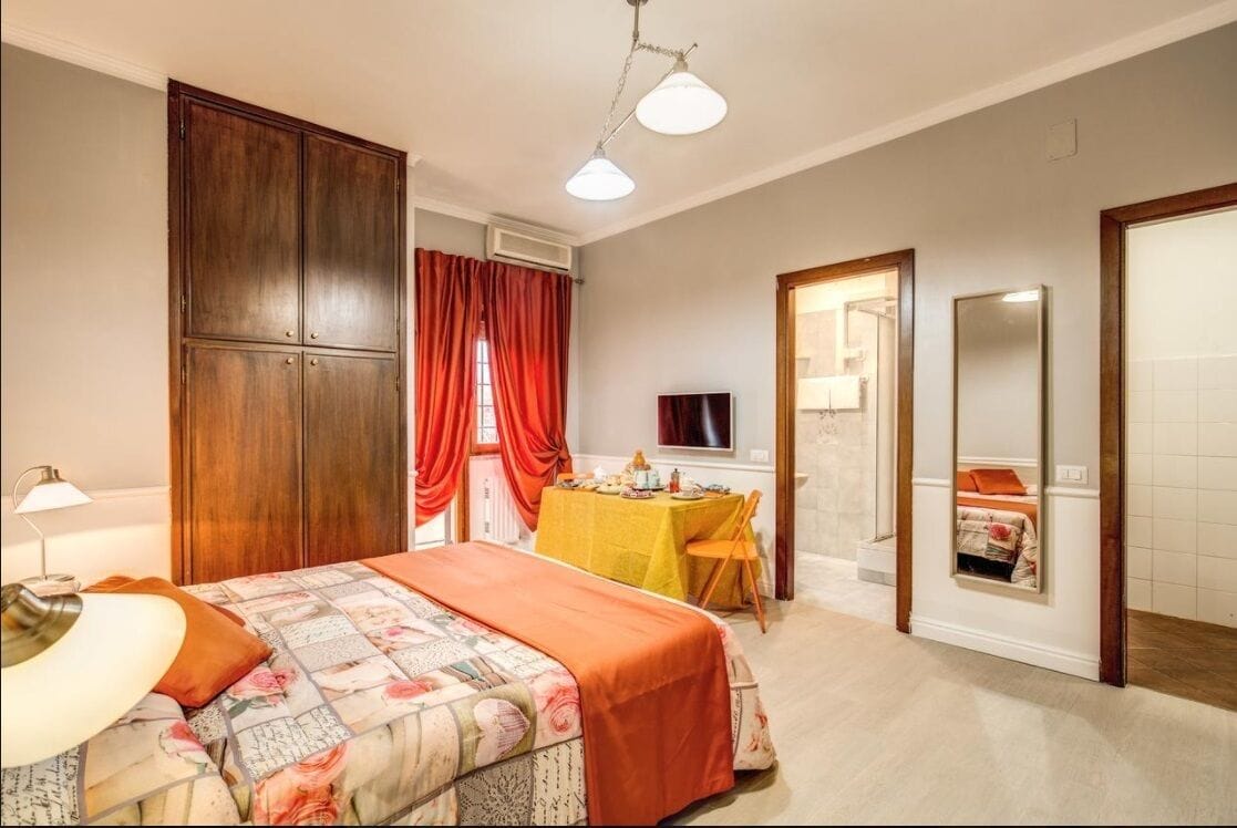 Un dormitorio con una cama, una mesa con sillas, un espejo y un armario.