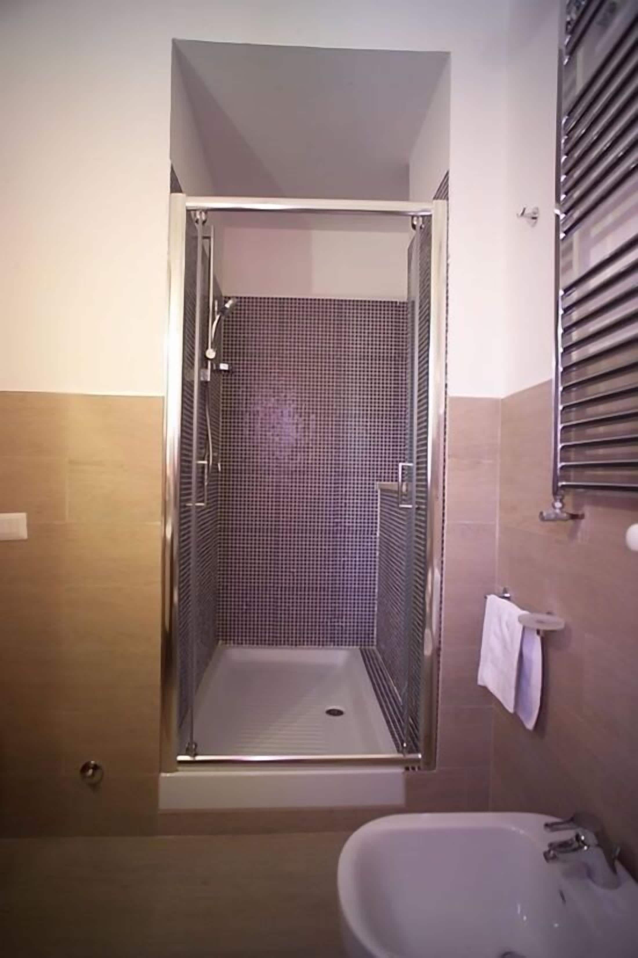 Une salle de bain avec une douche, un lavabo et un porte-serviettes.