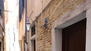 A narrow street with stone buildings, a wooden door with a brass handle, and a street lamp. - Residenza Ca' San Marco (Venice)