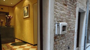 A hallway with a checkered floor, a brick wall, and a framed picture on the wall. - Residenza Ca' San Marco (Venice)