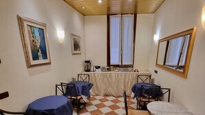 A dining area with checkered flooring, tables with blue tablecloths, and chairs with woven seats. - Residenza Ca' San Marco (Venice)