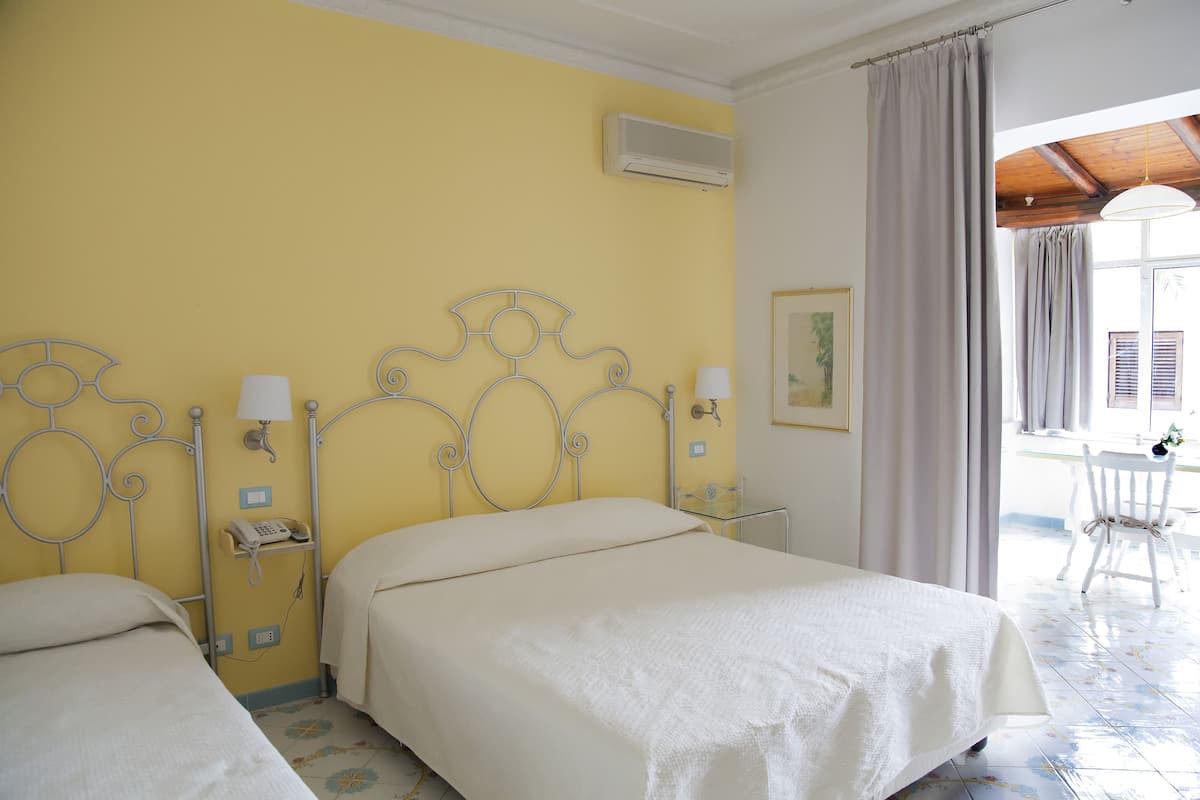 Habitación de hotel con dos camas, teléfono, lámpara y ventana con cortinas.