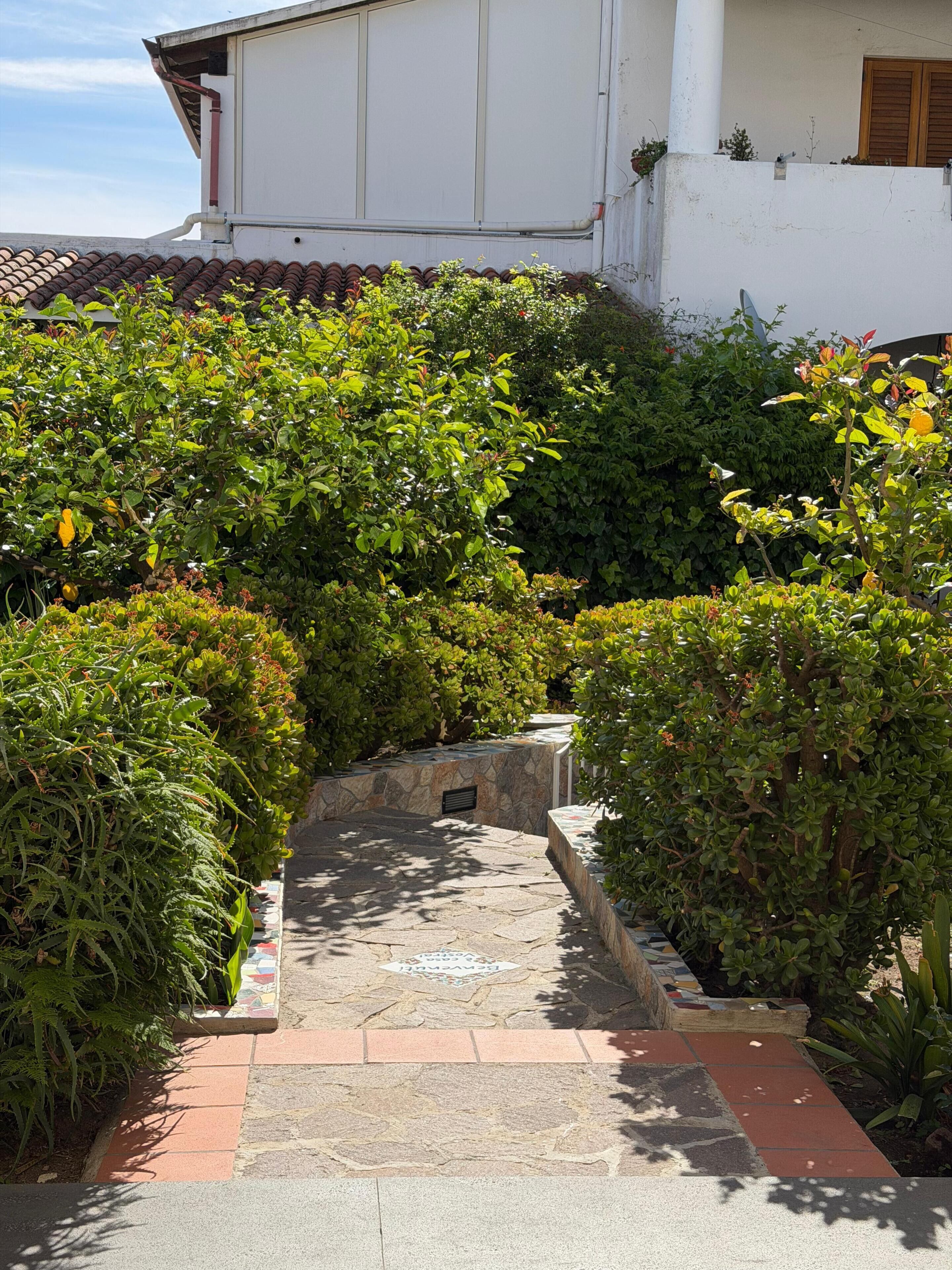 A pathway leading to a building with a tiled roof and white walls.